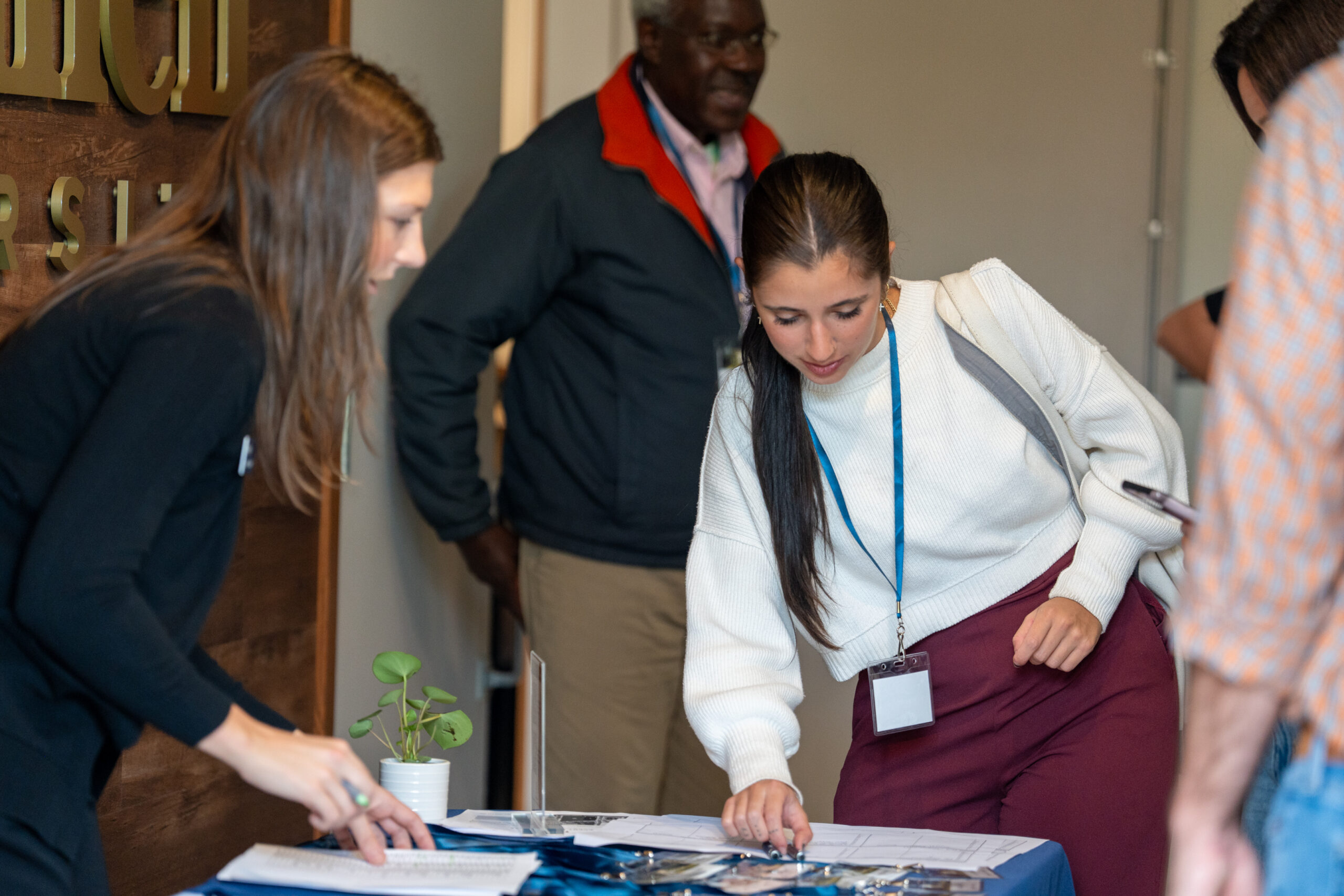 A woman leaning over the registration table at the 2025 NetVUE regional gathering at Bushnell University.